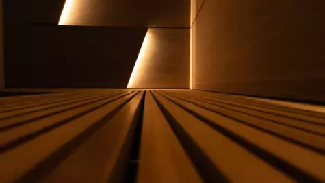 Una sezione di una sauna in legno illuminata con luce calda. 