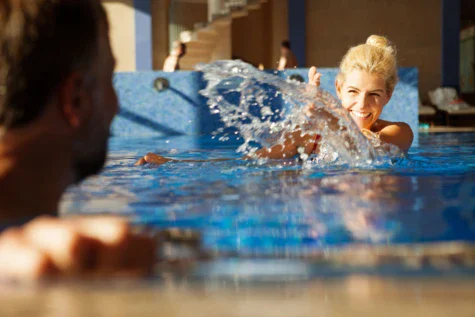 Donna che nuota e schizza acqua in una piscina.