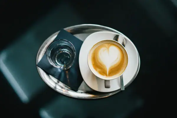 Una tazza di caffè con schiuma a forma di cuore su un piattino bianco.