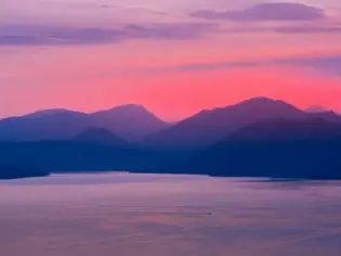 Corpo d'acqua con montagne in lontananza sotto un cielo sereno.