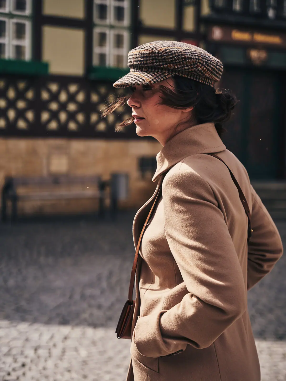 Una donna con un cappotto marrone e un cappello passeggia per Wernigerode, nella regione dell'Harz.