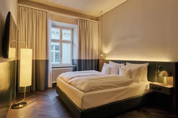 Un letto in una camera elegante con cuscini e copriletto ben sistemati.