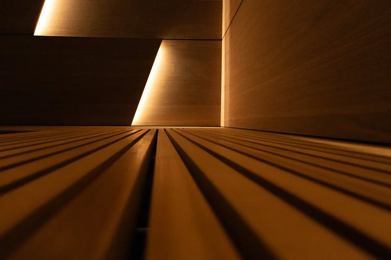Sauna Holzwand mit Beleuchtung und symmetrischen Linien.