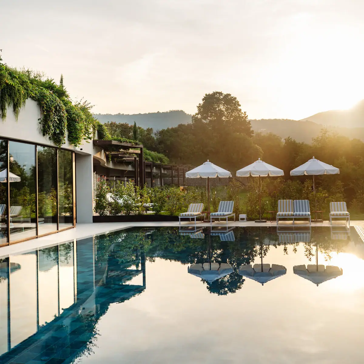 Piscina con sedie e ombrelloni davanti a un edificio.