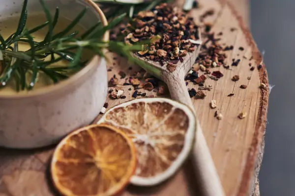 Eine Schüssel mit Flüssigkeit, Rosmarin und Gewürzen auf einer Holzoberfläche.