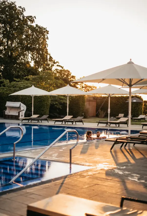 Gruppo di persone in una piscina all'aperto con alberi intorno.