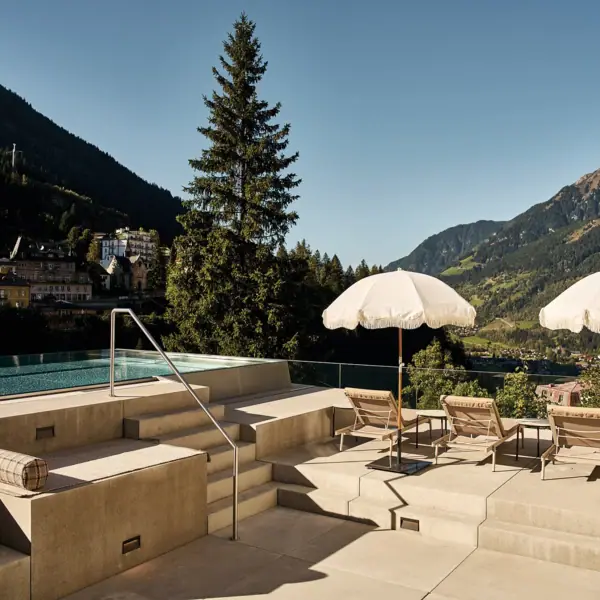 La piscina all’aperto dello SPA-ROSA di Bad Gastein, con ombrelloni e sedie a sdraio in una giornata di sole.
