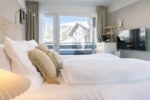 Ein Bett mit Kissen vor einem Fenster in einem stilvoll eingerichteten Raum.