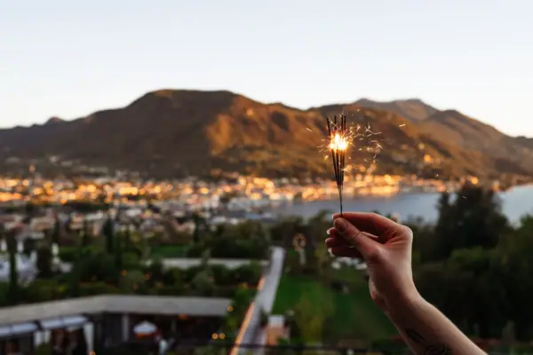 Una persona tiene in mano una candela magica a Capodanno sul Lago di Garda.