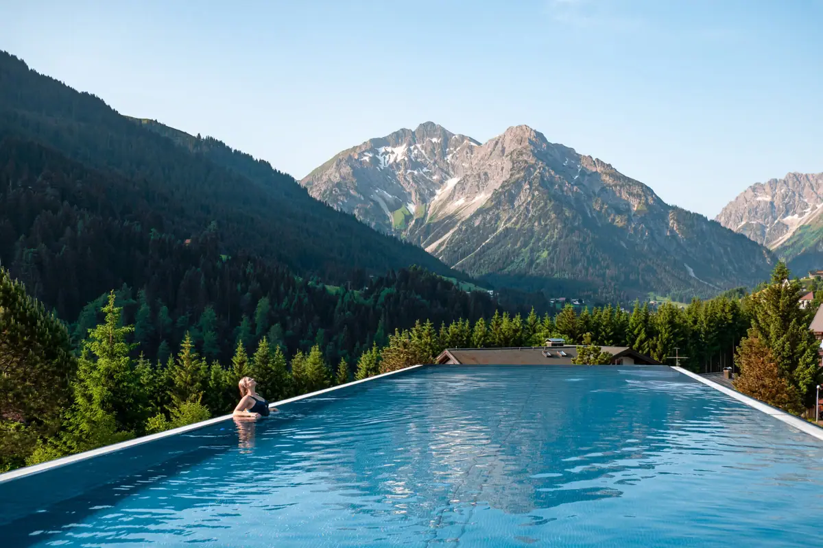 Hotel benessere in Austria Una persona in una piscina con le montagne sullo sfondo.