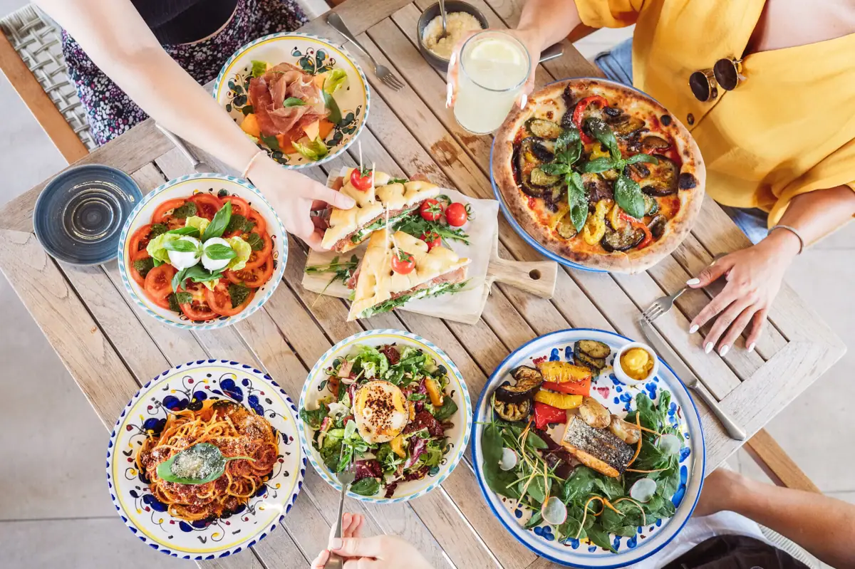 Colorata tavola mediterranea all’Hotel A-ROSA Lago di Garda con pizza, pasta, insalate fresche e piatti gourmet