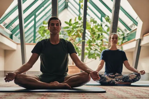 Un uomo e una donna sono seduti su dei tappetini da yoga.