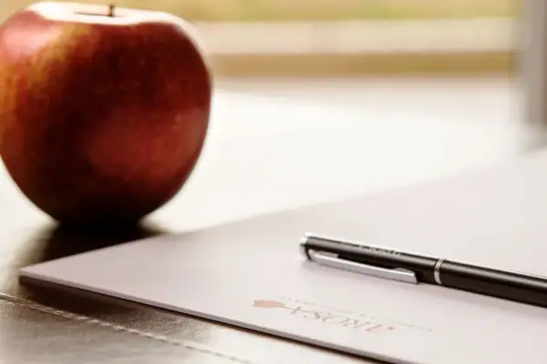 Ein Stift auf einem Blatt Papier neben einem Apfel.