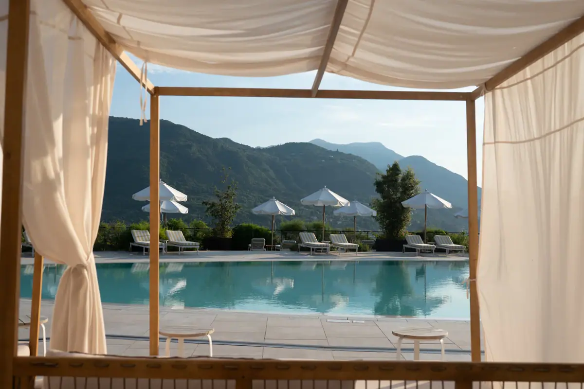 A-ROSA Lago di Garda Piscina con sedie e ombrelloni.