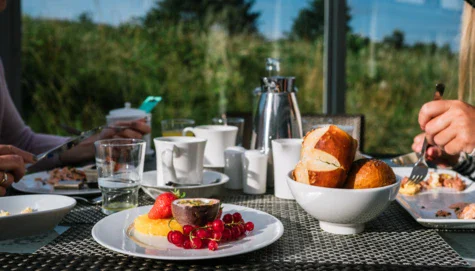 Piatto di cibo su un tavolo con frutta e una tazza di caffè.