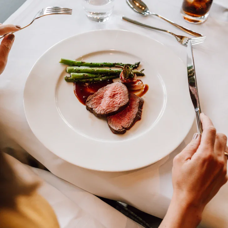 Persona che mangia un piatto di cibo con forchetta in un ristorante.