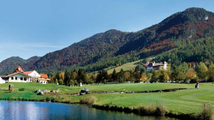 Lago circondato da montagne con una casa in primo piano.