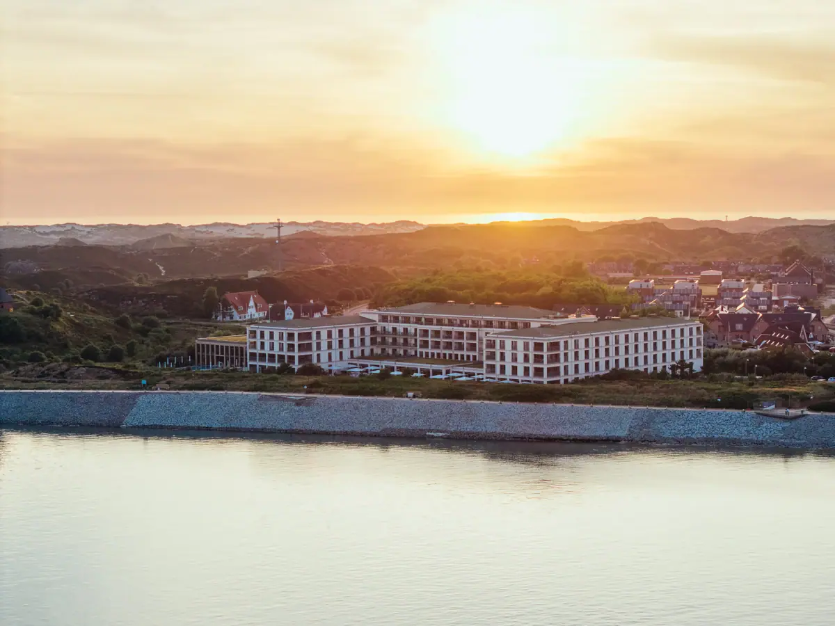 Un edificio in riva a uno specchio d'acqua all'aperto, con il cielo dell'alba.