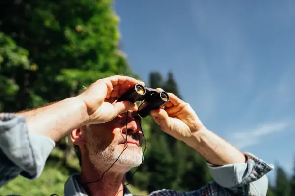 Un uomo guarda attraverso un binocolo.