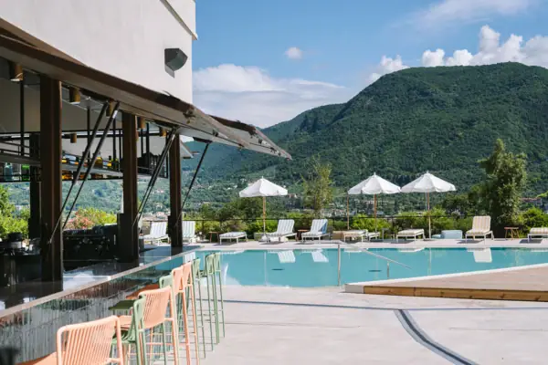 Piscina con sedie e ombrelloni accanto a un edificio.