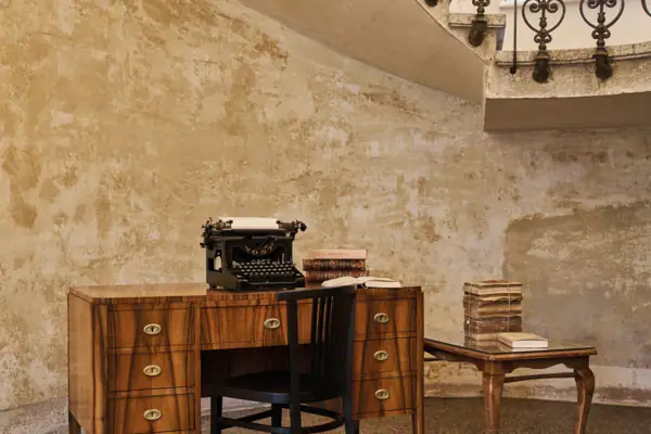 Una scrivania con una macchina da scrivere e un tavolo con libri.