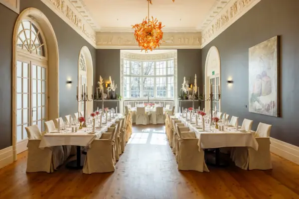 Una sala con tavoli e sedie all’A-ROSA Travemünde.