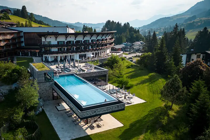 Ein Außenpool in einem Hotel mit Bäumen und klarem Himmel im Hintergrund.