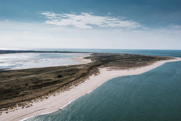 Spiaggia sabbiosa con acqua e cielo nuvoloso.