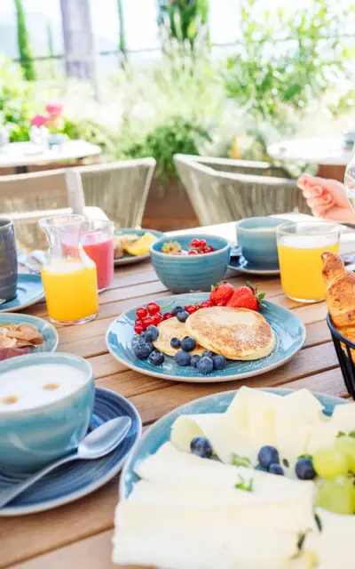 Tavolo imbandito con varietà di cibi per colazione, inclusi piatti, bevande e frutta.