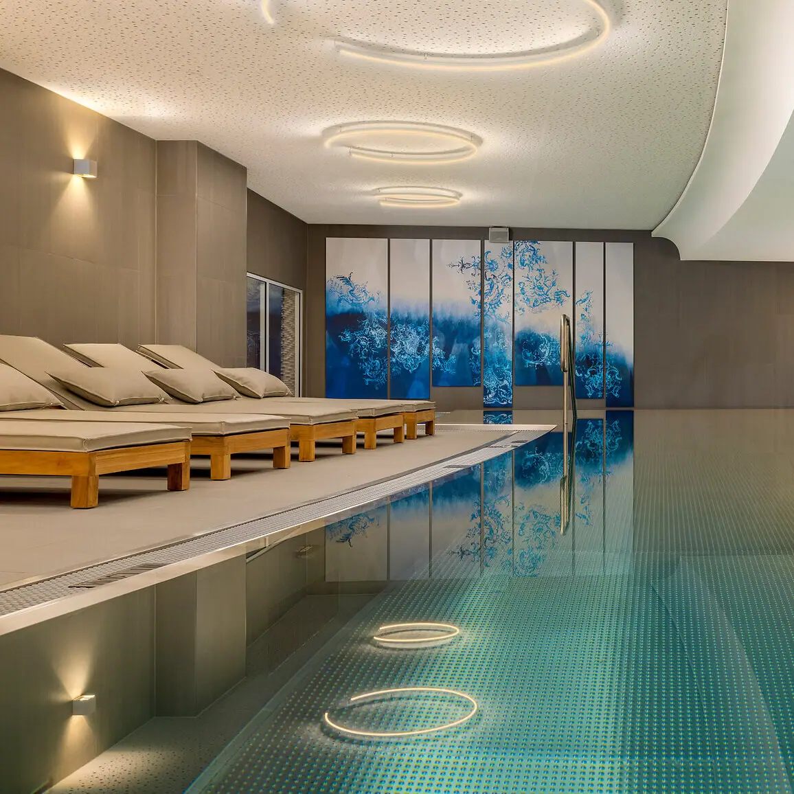 SPA-ROSA sul lago di Tegernsee Una piscina coperta con un’ampia terrazza e sedie a sdraio.