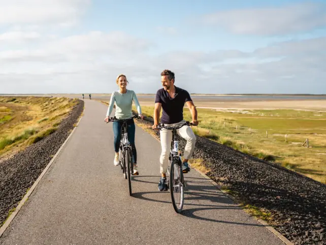 Uomo e donna che pedalano su una strada.