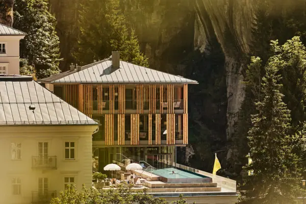 Edificio con piscina al centro, circondato da alberi e piante.