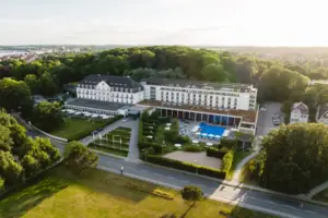 Un grande edificio bianco con piscina e alberi.